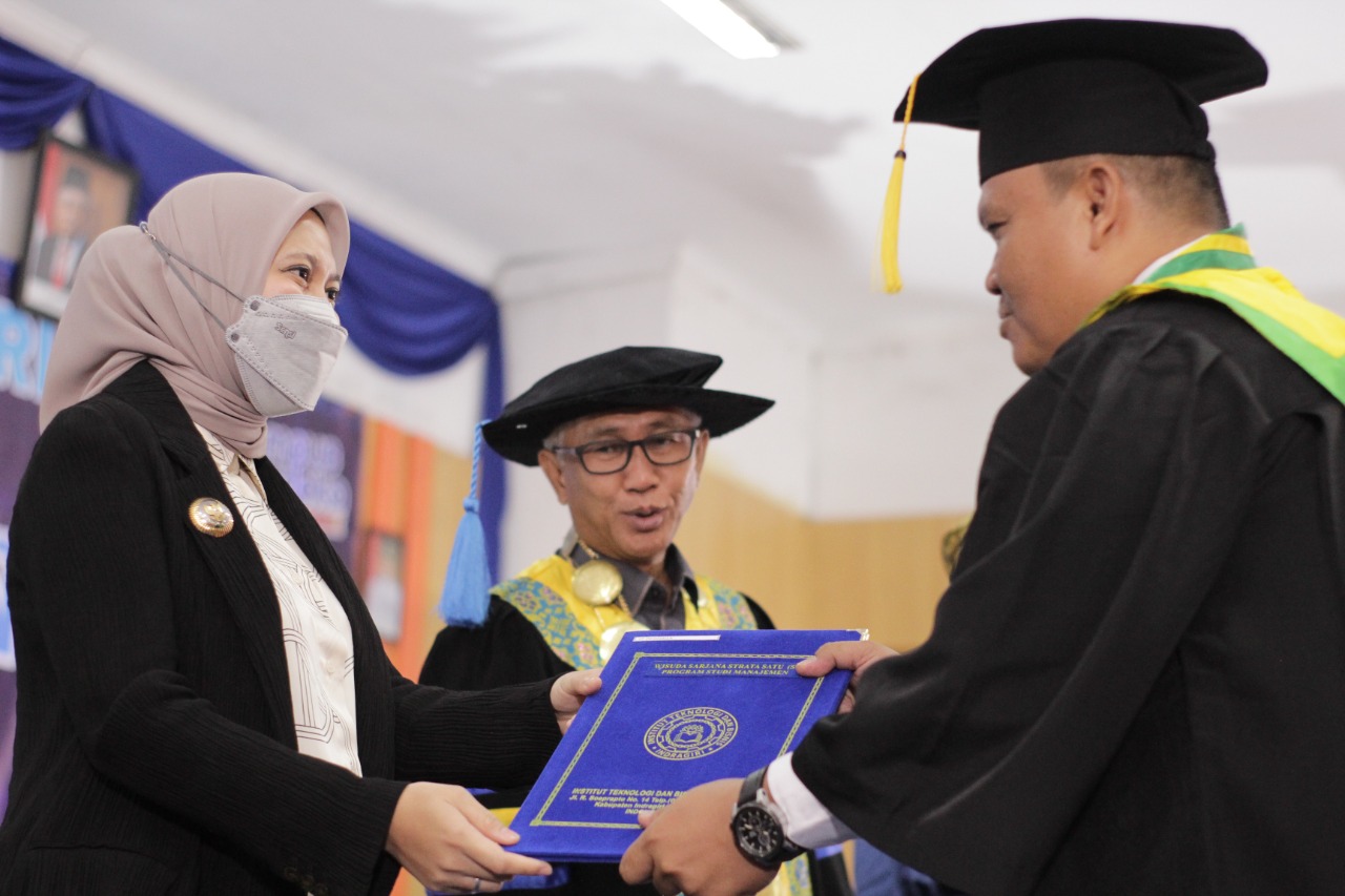Bupati Inhu, Rezita Meylani Yopi SE didampingi Rektor ITB Indragiri, Raja Marwan Indra Saputra SE MSi saat menyerahkan ijazah salah seorang wisudawan, Selasa (13/12/2022).