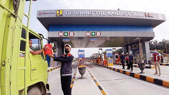 Petugas dari HK membagikan suvenir kepada pengendara yang melintas di gerbang tol Kandis Utara pada hari pertama dibuka, Ahad (20/2/2022) sebagai bagian ruas tol Pekanbaru-Dumai.