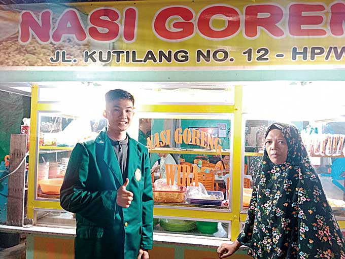 Mahasiswa Umri Yustian Pemersatu Zebua foto bersama pelaku usaha nasi goreng Wira di Jalan Kutilang, Kampung Melayu, Kota Pekanbaru, Selasa (24/1/2023).