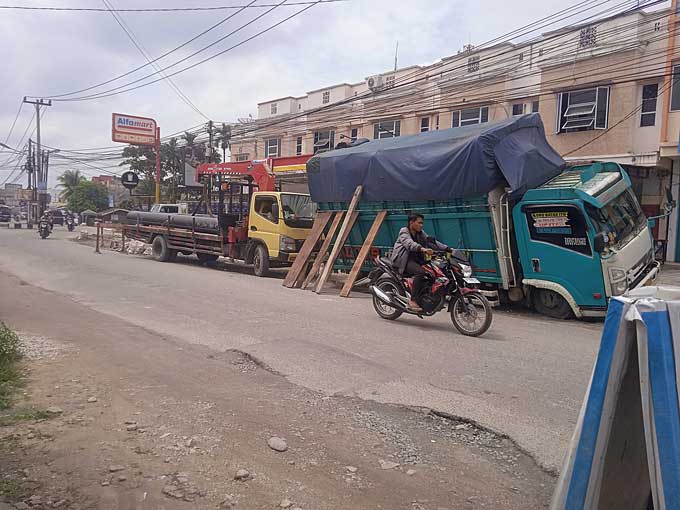 Pengendara melintas di dekat lokasi truk terperosok ke dalam bekas galian proyek di Jalan Rambutan, Kecamatan Marpoyan Damai, Jumat (13/1/2023).