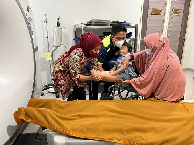 Tim Dokter dari Biddokkes Polda Riau Kompol dr Firmansyah D Anggara menggendong Fajri (7), bocah penderita tulang kaca ke alat CT-Scan di RS Awal Bros Ahmad Yani, baru-baru ini.