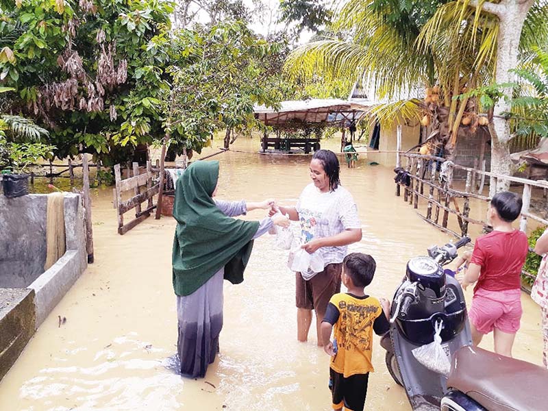 BANTUAN: Seorang kader Partai Demokrat Kuansing memberikan bantuan kepada warga saat banjir melanda Kelurahan Muara Lembu, Kecamatan Singingi, Ahad (8/12/2019). (mardias chan/riau pos)