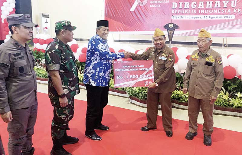 Bupati Siak Alfedri menyerahkan tanda mata kepada Ketua LVRI Dharmawi Chan dan anggotanya Paiman disaksikan Kajari dan Dandim di Gedung Kesenian Daerah Siak pada Rabu (16/8/2023).