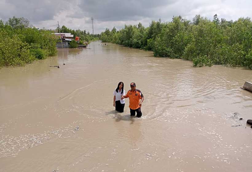 Salah seorang jajaran BPBD Kepulauan Meranti membantu seorang siswa melewati ruas Jalan Lingkar Dorak yang digenangi banjir rob akhir tahun lalu.