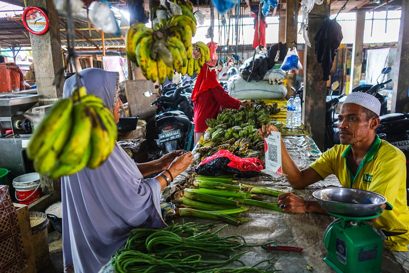 Dengan menggunakan gawai, pembeli memindai Quick Response Code Indonesian Standard (QRIS) saat bertransaksi di Pasar Limapuluh, Pekanbaru, baru-baru ini. Pasar Limapuluh merupakan salah satu dari tujuh pasar rakyat di Kota Pekanbaru yang menerapkan pembay