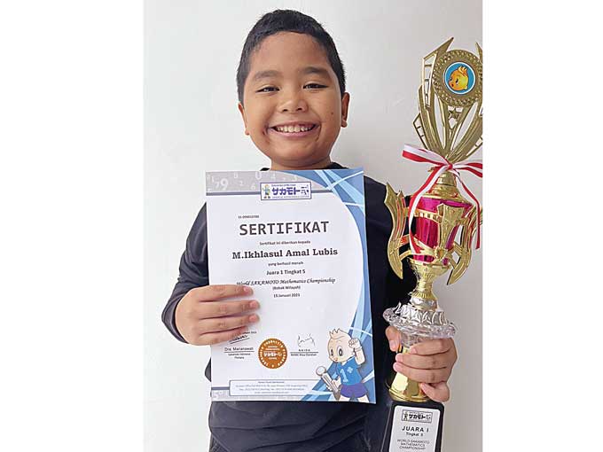 Muhammad Ikhlasul Amal Lubis tersenyum lebar saat menerima sertifikat dan piala kejuaraan matematika Sakamoto dan berhasil meraih juara I di tingkat Provinsi Riau, baru-baru ini.