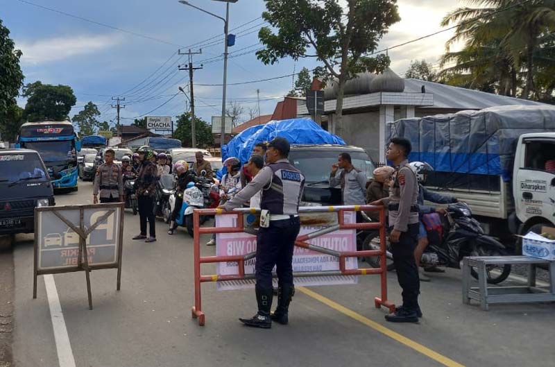 Petugas dari kepolisian dan dinas perhubungan mengatur lalu lintas di Ketinggian, Sarilamak, Kecamatan Harau, Kabupaten Limapuluh Kota, Provinsi Sumatera Barat, Kamis (28/12/2023). Jalur Riau-Sumbar sempat ditutup 10 jam karena petugas membersihkan longso