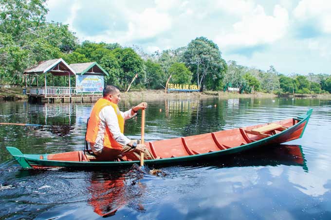 Bupati Kepulauan Meranti H Muhammad Adil saat menggunakan sampan ketika menikmati alam Telaga Air Merah, Sabtu (14/1/2023).