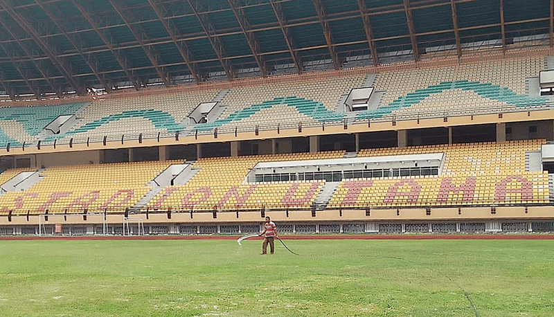 Pekerja menyiram rumput lapangan Stadion Utama Riau, Senin (2/10/2023). Stadion ini disterilkan hingga November 2023.