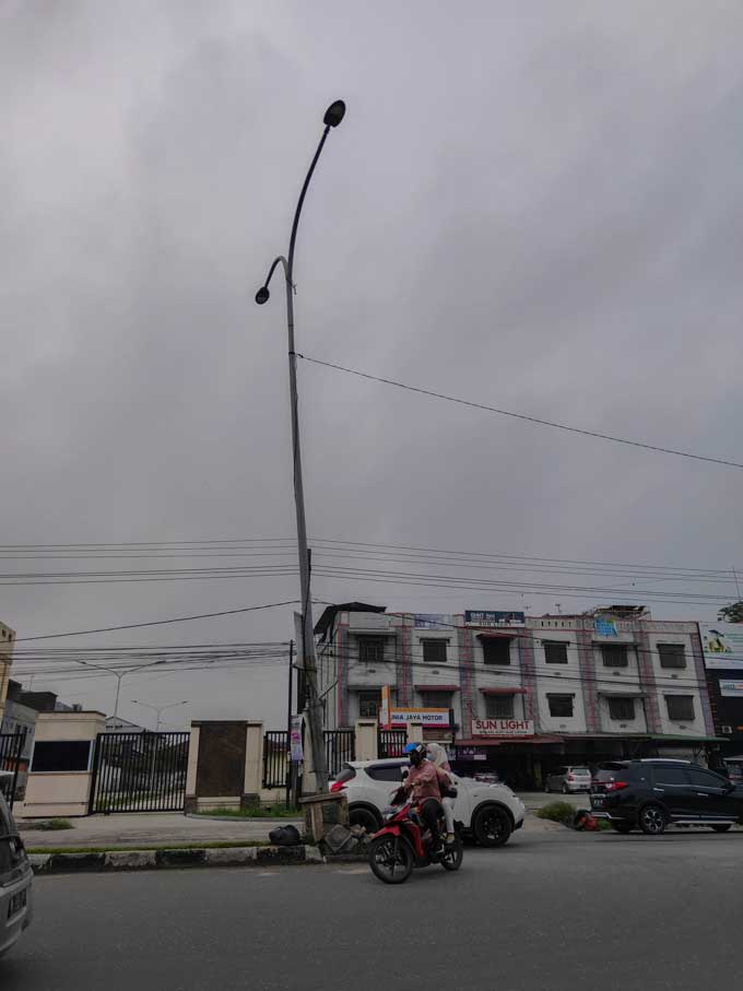 Tiang lampu penerangan jalan umum miring di Jalan HR Soebrantas, Jumat (22/10/2021).