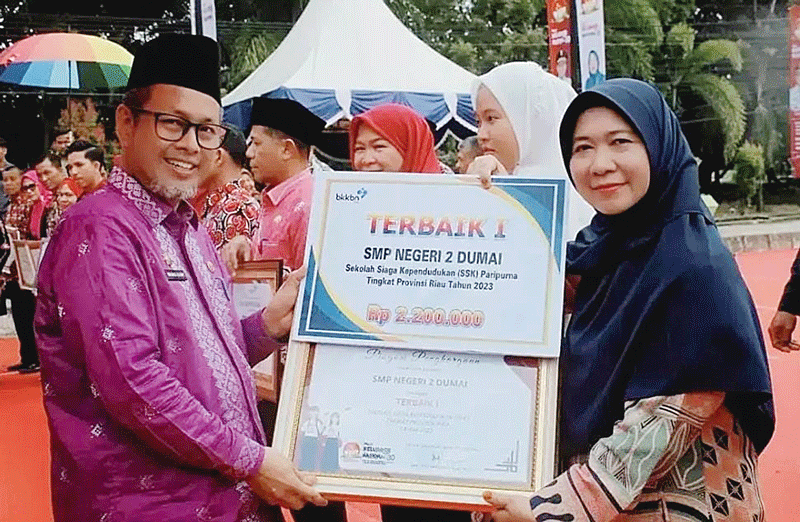Kepala SMPN 2 Dumai Saidatun Syabibah menerima penghargaan yang diserahkan Asisten PemerinÂ­tahan dan Kesejahteraan Rakyat Setdaprov Riau Drs H Masrul Kasmy, Sabtu (5/8/2023).
