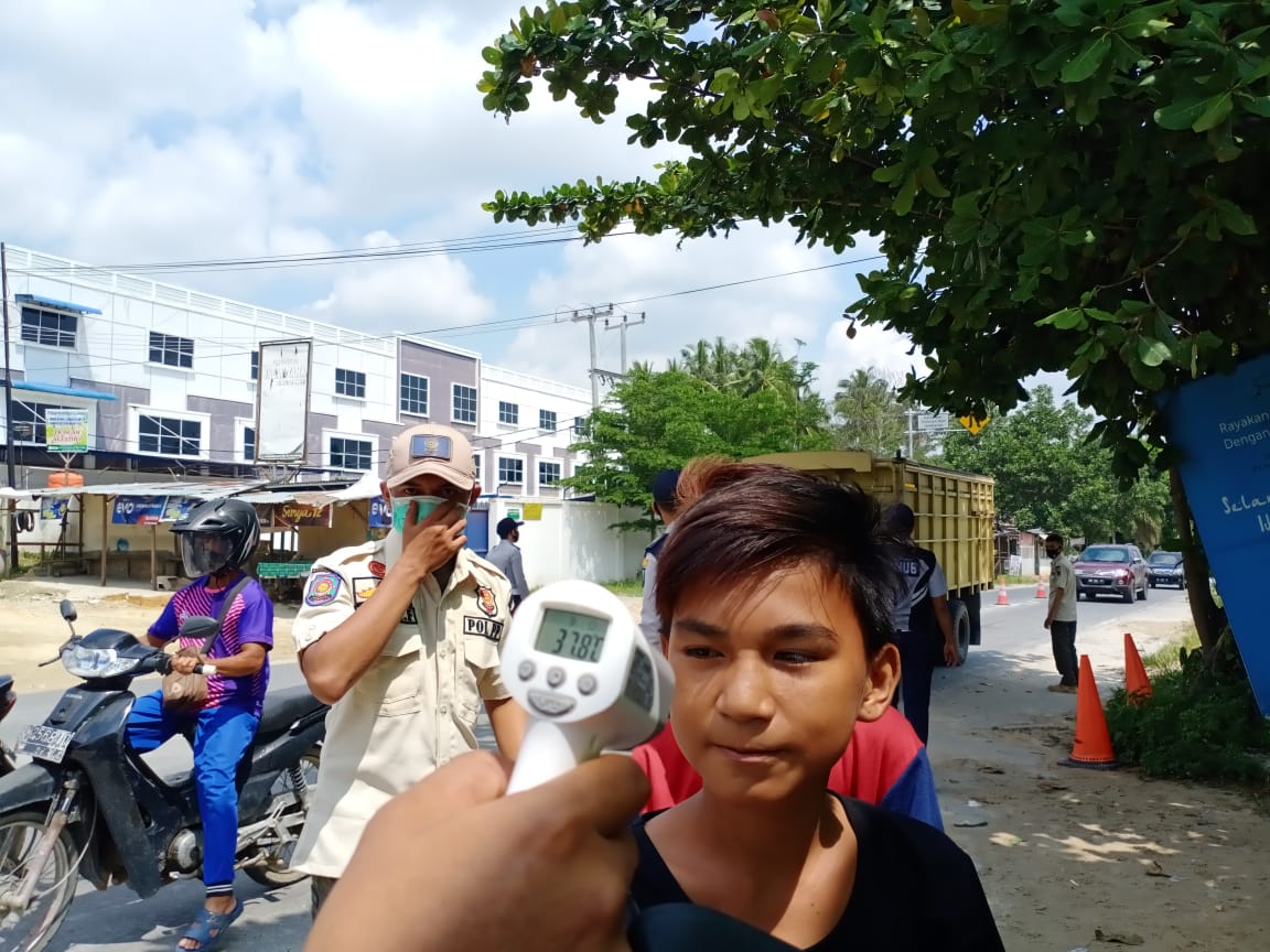 Petugas gabungan saat mengukur suhu pengedara yang tidak memakai masker di Jalan Garuda Sakti, Ahad (19/4/2020). (SOFIAH/RIAUPOS.CO)
