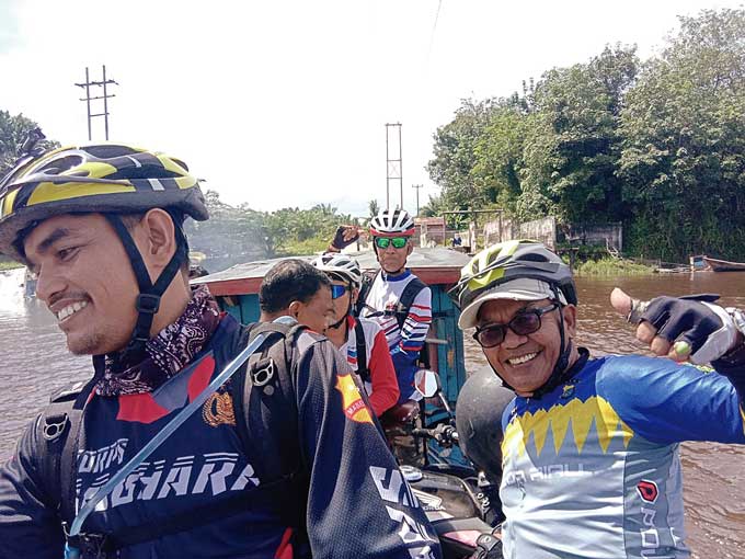 Anggota Komunitas Kospec menaiki pompong saat mengikuti gowes, baru-baru ini.