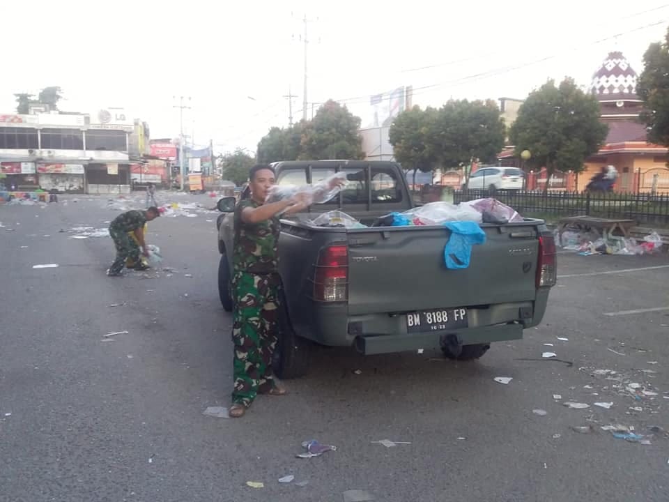 Beberapa Anggota TNI AD membersihkan sampah di Pasar Air Tiris pada Ahad (24/5/2020). (DANDIM 0313/KPR UNTUK RIAUPOS.CO)