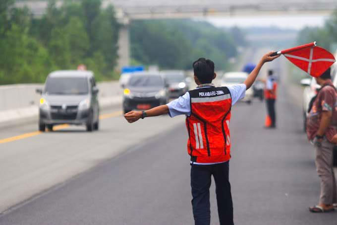 Petugas Tol Pekanbaru-Dumai memberi imbauan kepada pengendara untuk menjaga batas kecepatan dengan cara mengibarkan bendera, Kamis (22/12/2022).