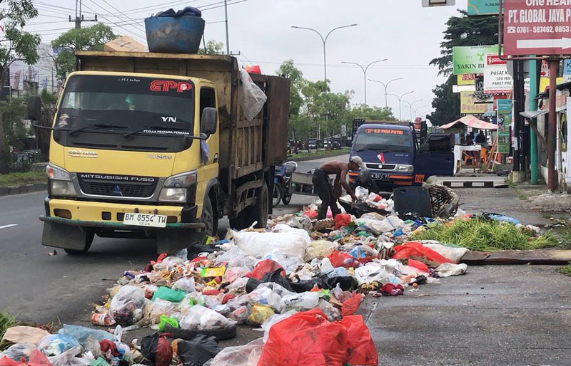 Pekerja mengangkut sampah yang menumpuk di pinggir Jalan HR Soebrantas di depan halte simpang Jalan Delima, Rabu (30/8/2023) pagi.