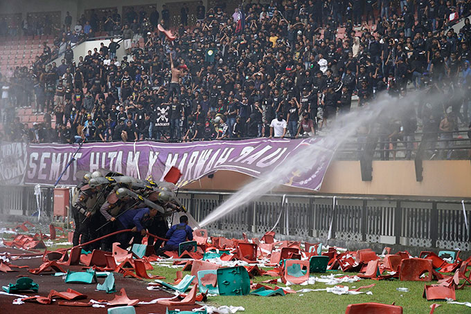 Petugas pemadam kebakaran menyemprotkan air untuk memadamkan api yang dinyalakan suporter saat laga PSPS menghadapi PSMS di Stadion Utama Riau, Kamis (22/9/2022). Suporter menyalakan flare, merusak dan membakar kursi stadion