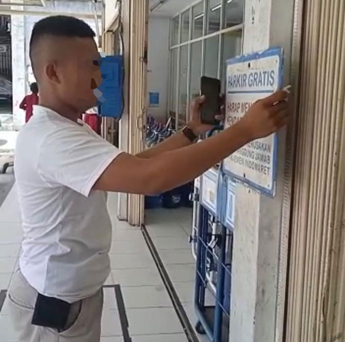 Tangkapan layar salah seorang yang mengaku koordinator parkir menurunkan spanduk tulisan parkir gratis di Indomaret, Ahad (19/9/2021).