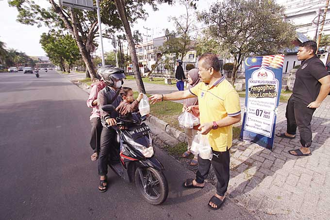Wakil Konsulat Malaysia Pekanbaru Awaluddin Mohd Nasir membagikan bubur lambok kepada masyarakat yang melintas di depan Kantor Konsulat Malaysia, Pekanbaru, Jumat (7/4/2023).