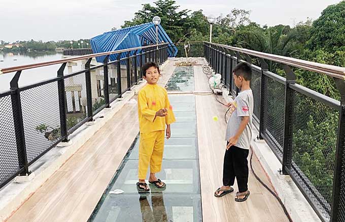 Dua anak berdiri di jembatan kaca (Skywalk) Tengku Buwang Asmara. Ke depan, setiap masyarakat yang akan melewati akan menggunakan alas kaki khusus, beberapa waktu lalu.