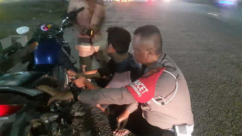 Anggota Satlantas Polresta Aiptu Arianto menunggu motor warga yang mogok sampai selesai diperbaiki pada malam Iduladha 1444 Hijriah, Rabu (28/6/2023).