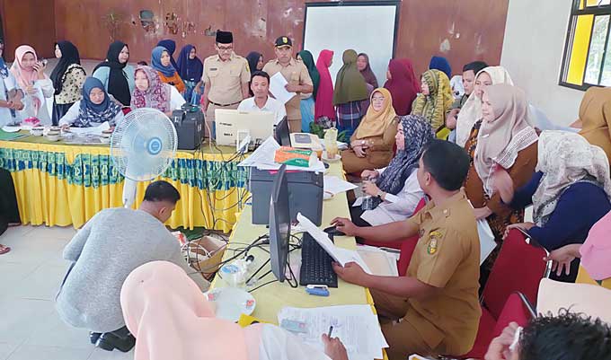 Plt Camat Hulu Kuantan Nasrul SSos MSi mendampingi pegawai Disdukcapil saat warga ramai mengurus adminduk di aula Kantor Camat Hulu Kuantan, Selasa (28/2/2023).
