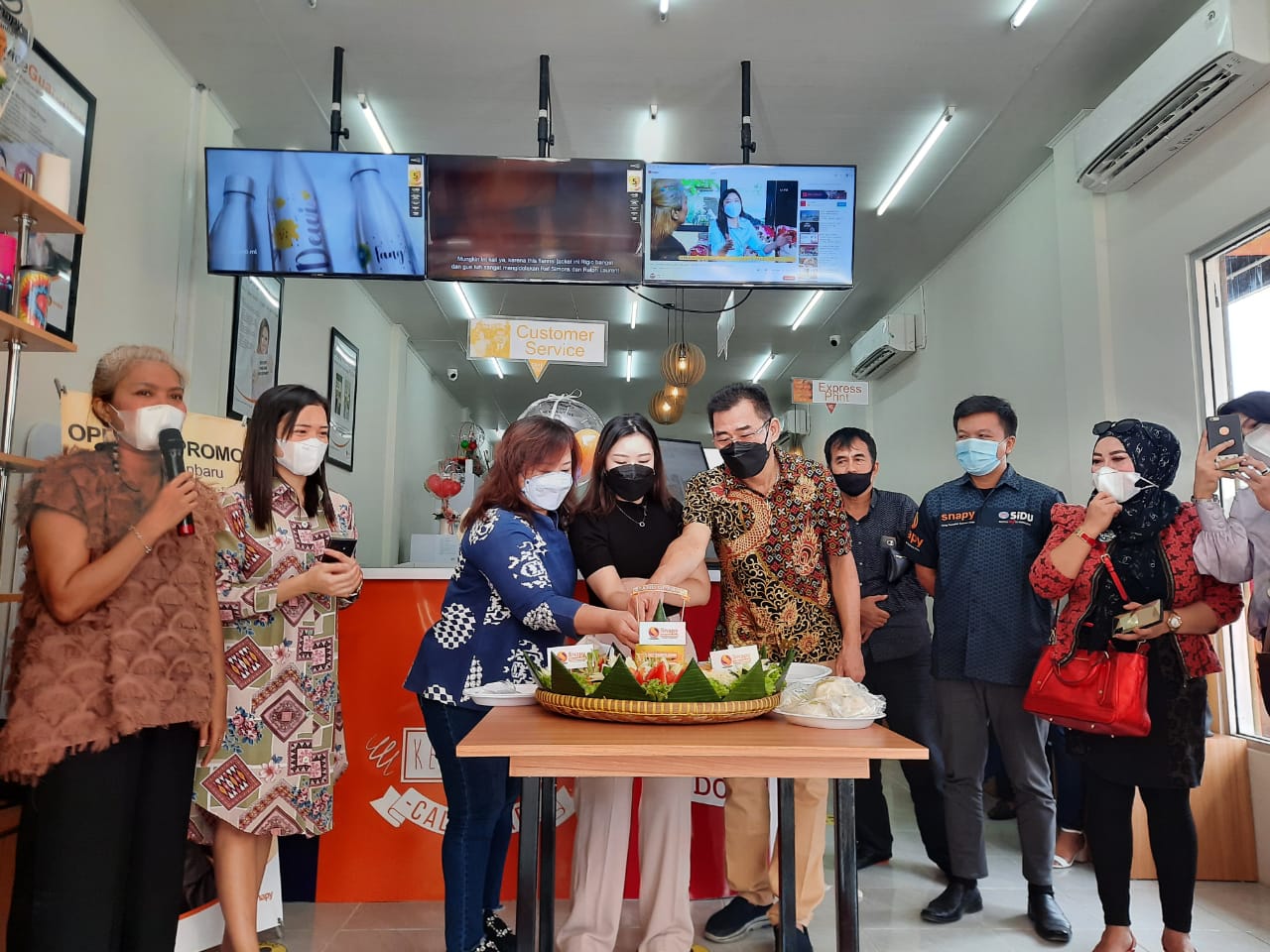 Owner Snapy Pekanbaru Michelle W Kostan (tengah) ditemani kedua orang tuanya saat memotong tumpeng dalam  rangka grand opening Snapy Pekanbaru, Jalan Tuanku Tambusai, Sabtu (17/7/2021)/MUJAWAROH ANNAFI.