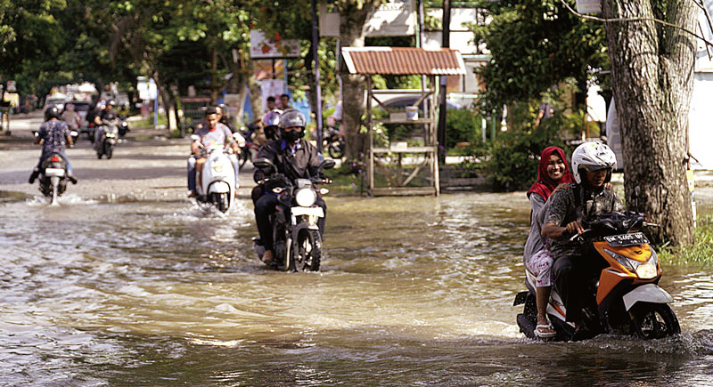 Pengendara sepeda motor melewati genangan banjir di Jalan Cipta Karya, baru-baru ini.