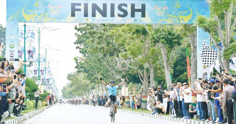 Atlet Maulana Atsnan Al Hayat dari Nusantara Cycling Team mengangkat kedua tangannya saat mencapai garis finish, meraih juara pertama pada etape kedua Tour de Siak, Ahad (3/12/2023).