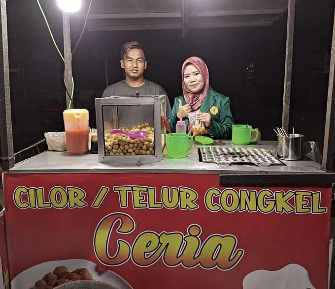 Mahasiswi Umri Putri Handayani foto bersama Doni , pelaku bisnis UMKM cilor/telor congkel ceria di Jalan Imam Munandar, Tangkerang Timur, Tenayan Raya, tepatnya di depan Taman Pancing Alam Mayang, Pekanbaru, Kamis (19/1/2023).