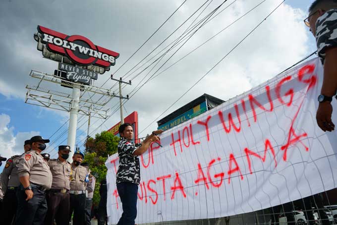 Massa aksi memasang spanduk di depan pintu masuk Holywings Pekanbaru, Jalan Soekarno-Hatta terkait promo minuman keras yang dilakukan Holywings Indonesia, Senin (27/6/2022).