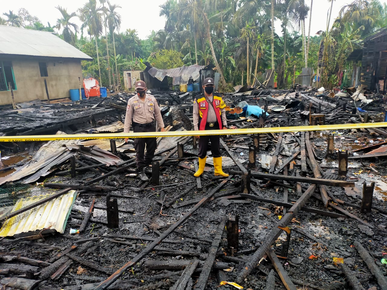Personel kepolisian dari Polsek Gaung Anak Serka memasang garis polisi di lokasi kebakaran, Sabtu (24/10/2020). POLSEK GAUNG ANAK SERKA FOR RIAUPOS.CO)