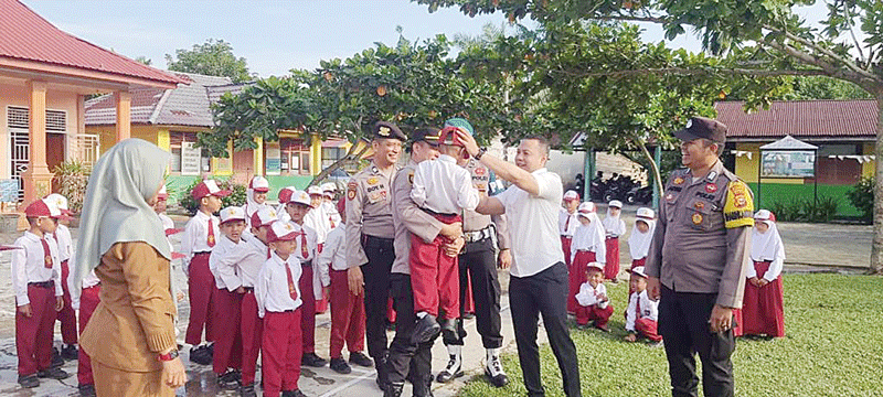 Kapolsek Perhentian Raja Ipda Riko Riski Masri memberikan bantuan sepatu kepada salah seorang murid kurang mampu di SDN 002 Perhentian Raja, Desa Kampung Pinang, Kecamatan Perhentian Raja, Senin (11/9/2023).