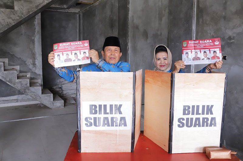 Bupati Rohul H Sukiman didampingi Istri Hj Peni Herawati Sukiman menunjukkan kertas surat suara sebelum menyoblos di TPS 10 Pilkades Pematang Berangan, Kecamatan Rambah, Kamis (8/12) pukul 09.30 WIB.