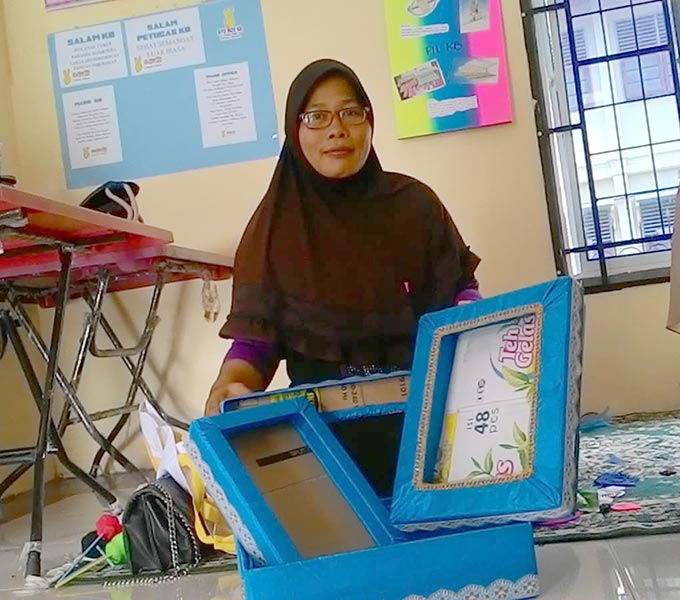 Evlinda Susanti tampak memperlihatkan hasil kreasinya membuat kotak hantaran dari kardus bekas, Sabtu (24/7/2021).