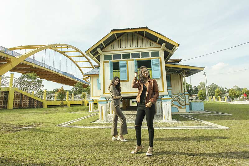 SEGERA DIPERBIKI: Wisatawan berfoto dengan latar belakang rumah singgah Tuan Kadi di Kampung Bandar Senapelan Pekanbaru, Rabu (22/2/2020). Rencananya rumah singgah Tuan Kadi ini akan diperbiaki melalui dana APBD murni 2020. (DOK.RIAUPOS)