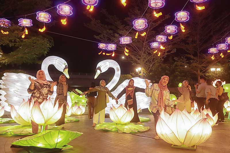 Pengunjung Mal Living World Pekanbaru menikmati keindahan lentera dengan berswafoto di lokasi iven The Biggest Lantern Festival in Riau 2023, Kamis (8/6/2023) malam. Iven yang menampilkan aneka tema seperti Dragon, Flower, Swan, Opera Girl, Gate and Bridg
