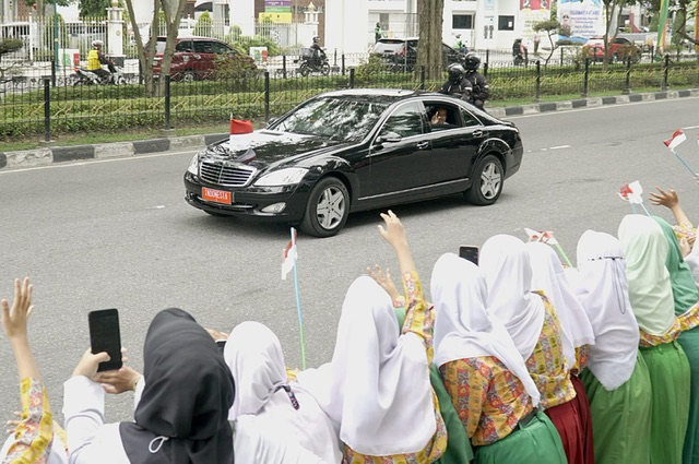 Siswa tampak memegang bendera merah putih melambaikan tangan kepada Presiden Jokowi saat melintas di Jalan Jendral Sudirman Pekanbaru, Rabu (4/1/2023).