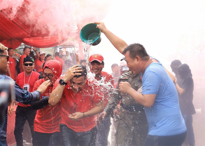 Bupati Meranti Muhammad Adil disiram warga ketika ingin menaiki becak motor untuk mengikuti Festival Perang Air, Kamis (26/1/2023) sore.