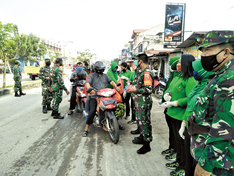 Jajaran Koramil 04 Mandau membagikan masker dan sabun kepada warga yang melewati Simpang Pokok Jengkol Duri, Rabu (15/4/2020). (HENNY ELYATI/RIAUPOS.CO)