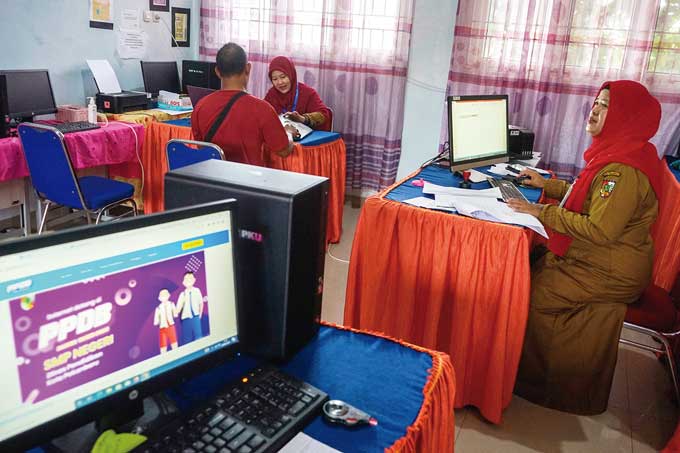 Guru membantu orang tua calon peserta didik pendaftarkan anaknya di SMP negeri secara online pada Penerimaan Peserta Didik Baru (PPDB) 2023 di SMPN 42 Pekanbaru, Senin (26/6/2023).