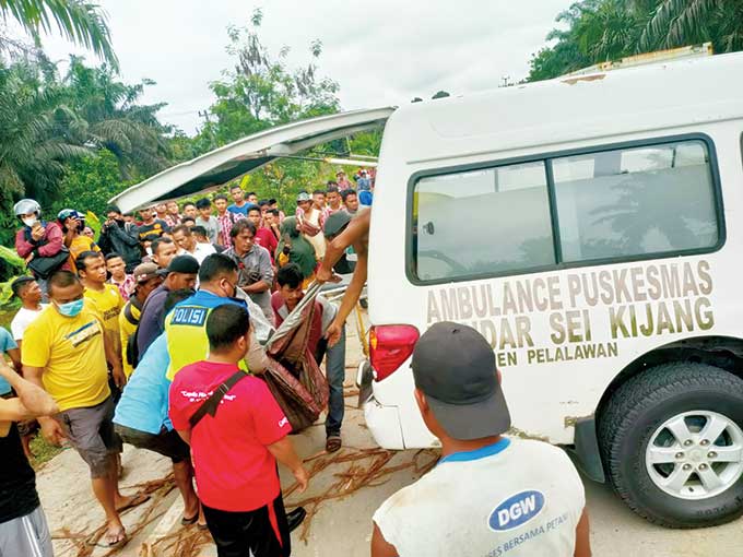Personel Sat Lantas Polres Pelalawan bersama Polsek Bandar Seikijang melakukan evakuasi jenazah dua korban kecelakaan truk pengangkut pakan ternak yang bertabrakan dengan truk bermuatan kayu balak di Jalintim KM 36+200 Kelurahan Seikijang, Kecamatan Banda