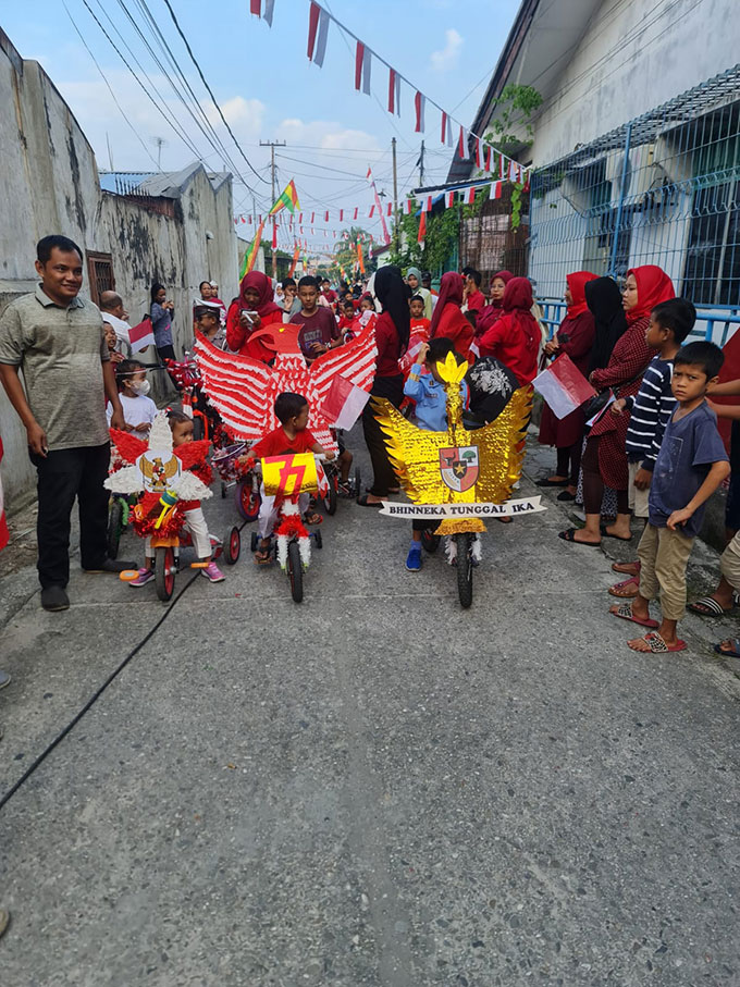 Warga Kampung Baru, Kecamatan Senapelan mengiringi anak-anak yang menaiki sepeda hias dan keliling kampung dalam rangka memeriahkan Hari Kemerdekaan ke-77 RI, Ahad (14/8/2022).
