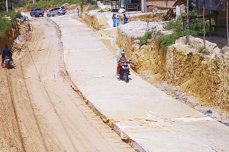 Rigid Jalan: Warga melintas di Jalan Badak Kecamatan Tenayan Raya Pekanbaru yang sedang dalam proses pengerjaan rigid beton. Proses rigid ini diharapkan akhir tahun ini sudah selesai dikerjakan. Foto diambil beberapa waktu lalu. (EVAN GUNANZAR/RIAU POS)