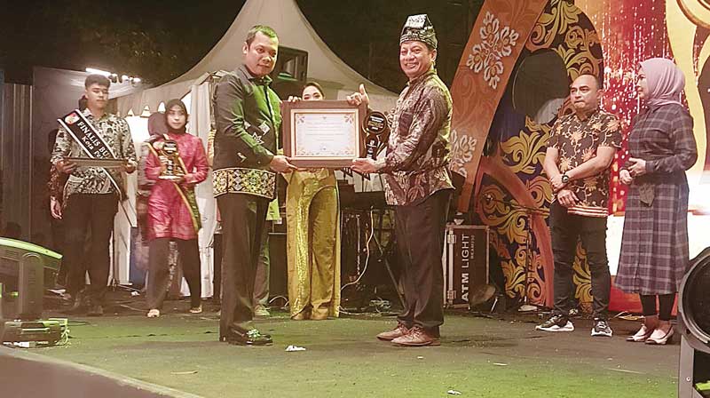 Pj Wali Kota Pekanbaru Muflihun (kiri) saat menyerahkan penghargaan Pekanbaru Tourism Award kepada Riyono Gede Trisoko (kanan) selaku generasi kedua yang mengelola Taman Rekreasi Alam Mayang, Ahad (14/5/2023).