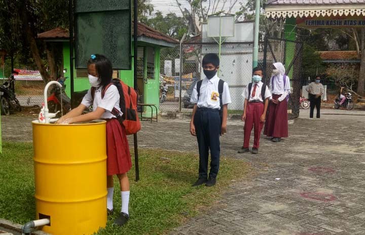 Hari pertama pembelajaran tatap muka SMPN 6 Pekanbaru pelajar dan guru mengikuti prokes dengan ketat. Nampak pelajar antre mencuci tangan sebelum lanjut pada prokes lanjutan, Senin (16/11/2020). (SYAHRUL MUKHLIS/RIAU POS)