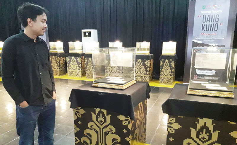 Edukator Museum Sang Nila Utama, Asadi Faizin menjelaskan salah satu seri uang kuno yang dipamerkan dalam pameran uang kuno, Ahad (10/12/2023).