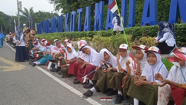Para siswa didampingi guru sekolah di Pekanbaru terlihat memegang bendera berukuran kecil yang mereka bawa untuk menyambut kedatangan Presiden Joko Widodo di gerbang keluar Bandara Internasional Sultan Syarif Kasim II Pekanbaru, Rabu (4/1/2023).