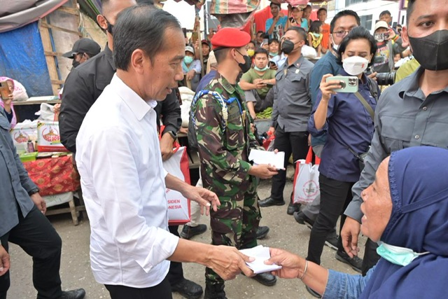 Presiden Joko Widodo membagikan bantuan sosial kepada warga setibanya di Pasar Bunda Sri Mersing, Dumai dalam kunjungan kerjanya pada hari kedua di Riau, Kamis (5/1/2023).