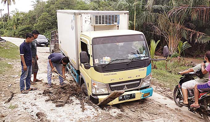 Akibat kondisi jalan lintas Kecamatan Bengkalis di Desa Kelemantan rusak parah mengakibatkan truk bermuatan es kristal terpuruk selama beberapa jam, Selasa (14/3/2023).